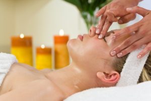 A young woman relaxing at a health spa while having a facial treatment